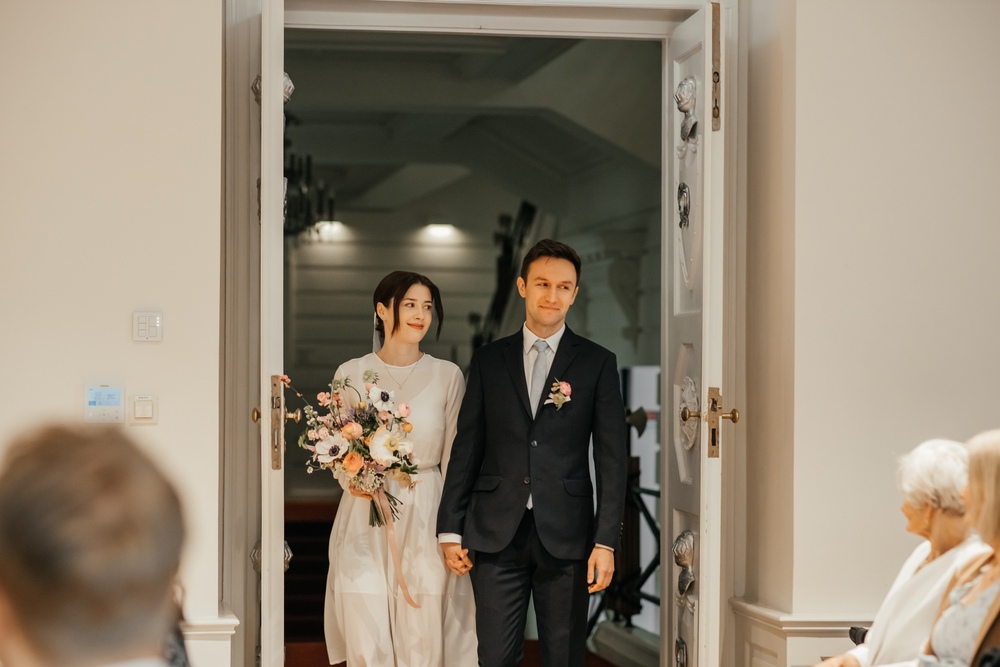 Nowożeńcy wchodzący do sali z uśmiechem na twarzach podczas ceremonii ślubu cywilnego