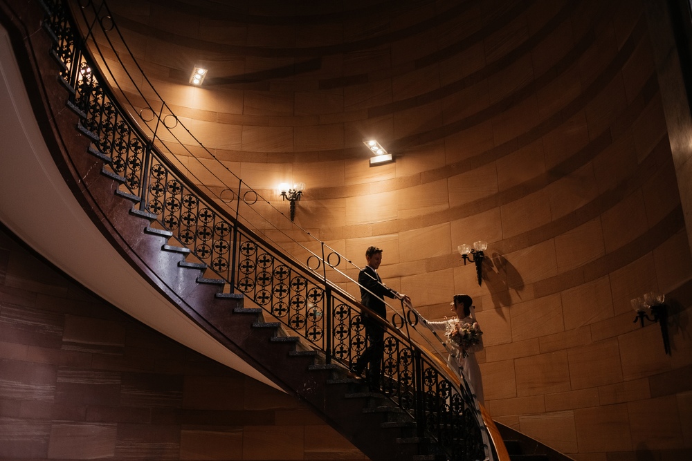 Romantyczna scena na kręconych schodach, gdzie para młoda dzieli się uściskiem, otoczeni pięknym wnętrzem Zamku Cesarskiego