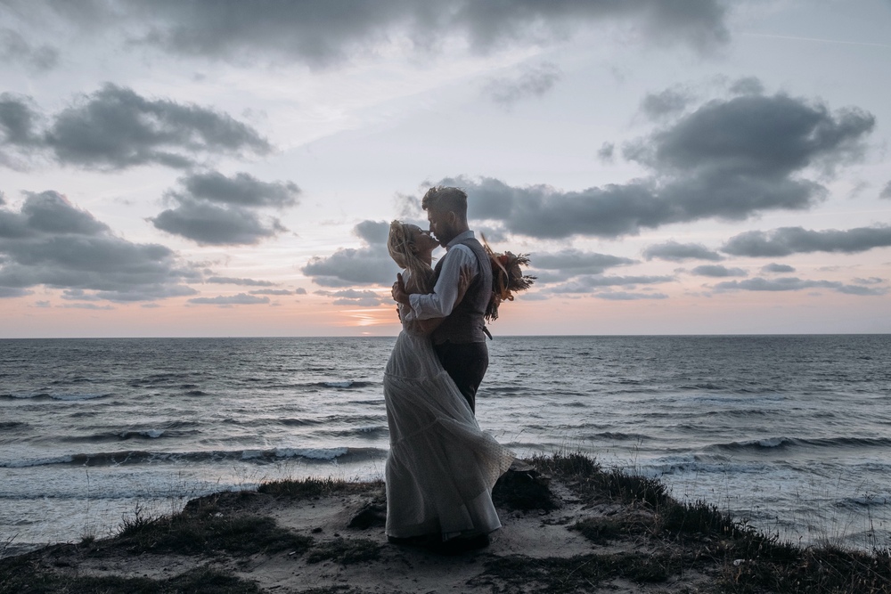 Pasjonujący pocałunek pary młodej w blasku wieczornego światła, podczas sesji ślubnej na Pomorzu"