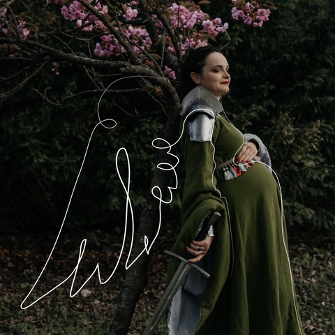Sesja ciążowa - kobieta w średniowiecznej sukni i zbroi na tle kwitnącego drzewa