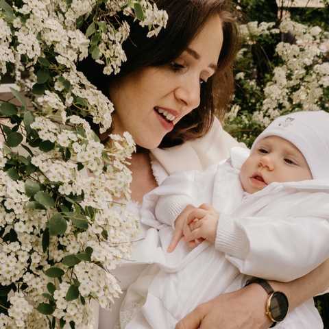 Sesja rodzinna - mama z noworodkiem na tle białych kwiatów