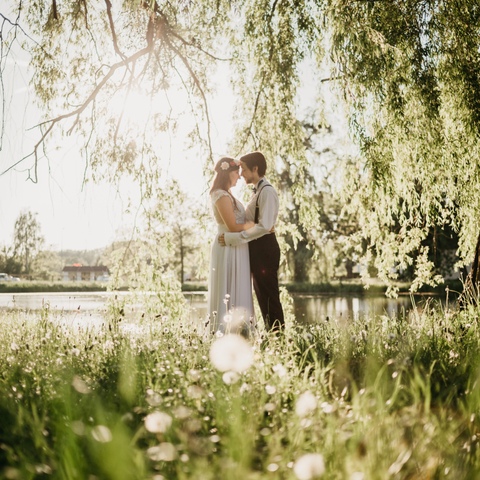Zdjęcia ślubne pary młodej w parku obejmującej się na tle stawu
