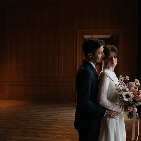Zdjęcie ślubne eleganckiej pary młodej z bukietem ślubnym w pustym pokoju