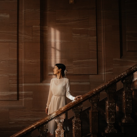 Zdjęcie ślubne eleganckiej panny młodej schodzącej po schodach pałacu