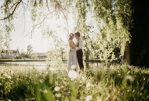 Zdjęcia ślubne Poznań - pan młody obejmuje swoją żonę pośród kwietnej łąki