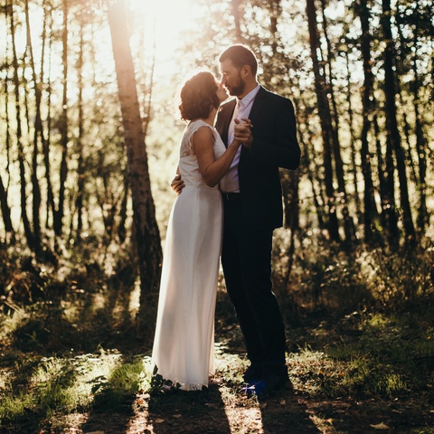 Zdjęcie ślubne pary młodej w rozświetlonym promieniami słońca lesie