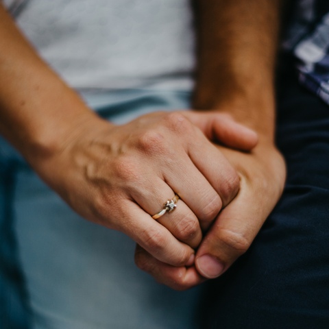 Sesja zdjęciowa dla par - splecione dłonie z pierścionkiem zaręczynowym